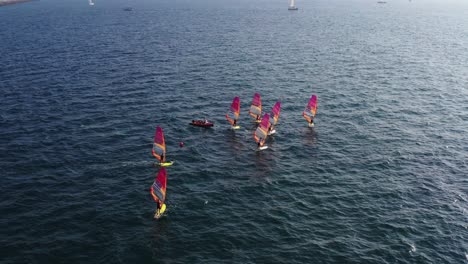 Multiple-windsurfers-standing-on-a-surfboard-on-the-Mediterranean-sea-with-colored-sails-on-a-sunny-day-in-Herzeliya-Israel-on-a-sunny-day
