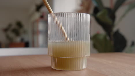Time-lapse-drinking-a-green-healthy-juice-through-a-sustainable-golden-metal-straw-from-a-design-drinking-glass-in-the-living-room-at-home