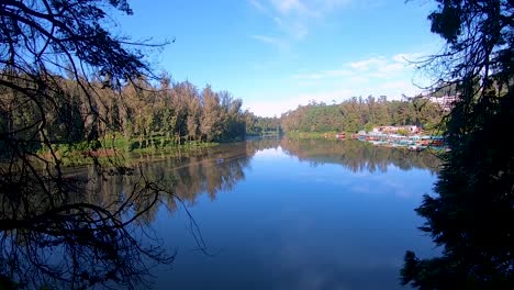 pristine-calm-water-lake-with-reflection-of-soothing-blue-sky-and-surrounded-by-green-forests-video-taken-at-ooty-lake-tamilnadu-india