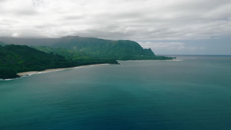 panoramic-aerial-over-seascape-and-mountains-as-backdrop-in-Kauai-island,-Hawaii,-USA