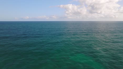 Drone-flying-over-turquoise-waters-of-Pacific-Ocean-towards-an-idyllic-postcard-sunny-sky