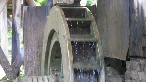Slow-motion-shot-of-rotating-water-mill-outdoors-with-splashing-water-during-sunny-day