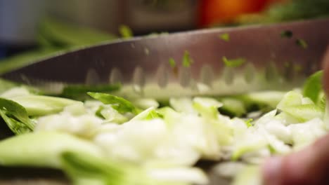 Detail-shot-of-an-Asian-chef-finely-chopping-leafy-green-vegetable-with-a-sharp-knife