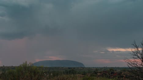 Un-Lapso-De-Tiempo-De-Nubes-De-Tormenta-Rodando-Sobre-Uluru-En-El-Interior-Australiano-Durante-La-Puesta-De-Sol