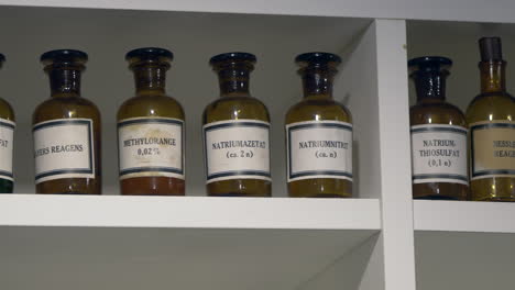 Close-up-shot-of-toxic-chemicals-preserved-in-retro-brown-bottles-standing-in-cupboard
