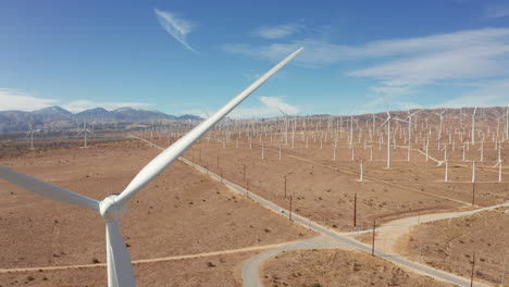 Camera-pulls-backwards-and-moves-through-propellers-of-windmill-in-desert-wind-farm