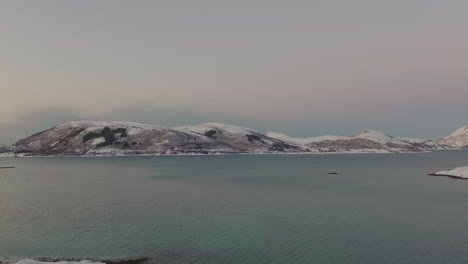 Vista-Aérea-De-La-Isla-De-Kvaloya-Con-Mar-En-Calma-En-Primer-Plano-En-Invierno-En-Noruega