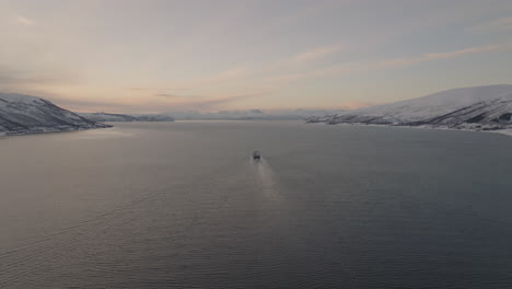 Bird's-Eye-View-Of-Cargo-Boat-Cruising-In-Fiord-Between-Snowy-Islands-In-Tromso,-Norway