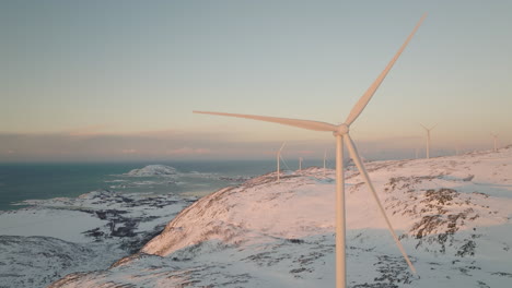 Aerial-pan-slomo---wind-farm-strategically-placed-on-snowy-mountain,-Arctic