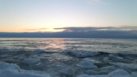 Waves-crashing-on-the-shore-on-a-winter-morning,-icebergs-ice-formations-floting-on-the-water