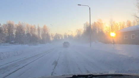 Driving-through-small-town-on-icy-winter-road-during-golden-sunset,-POV-shot