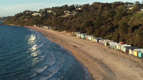 Slow-accent-and-rise-to-reveal-Mornington-beach-as-couple-walk-along-the-shoreline