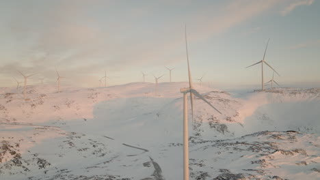 Aerial-pan-of-wind-farm-in-arctic-Norway-on-top-of-snow-covered-mountain