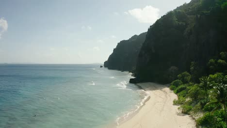 Aerial-Over-Tranquil-Beach-On-Black-Island-And-Steep-Forested-Cliffs