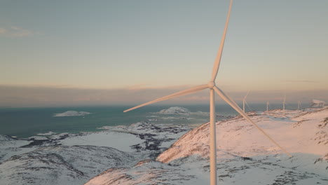 Wind-turbines-on-top-of-white-snowy-mountain-in-arctic,-golden-hour