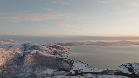 Vista-Aérea-Del-Fiordo,-Isla-Kvaloya-Con-Bosque-Cubierto-De-Nieve-Al-Atardecer-En-Noruega