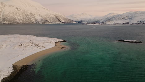 Drone-shot-tilting-up-to-reveal-beautiful-snowy-mountain-landscape,-Scandinavia