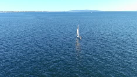Flying-over-a-sailboat-in-the-Pacific-Ocean-off-the-coast-of-Pacific-Palisades-California-|-Flyby-Aerial-Shot-|-Sunny-Afternoon