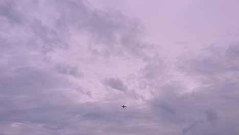 A-silhouetted-airplane-flying-with-a-stunning-evening-pink-and-purple-cloudy-evening-sky,-plane-flies-overhead-from-South-East-Asia