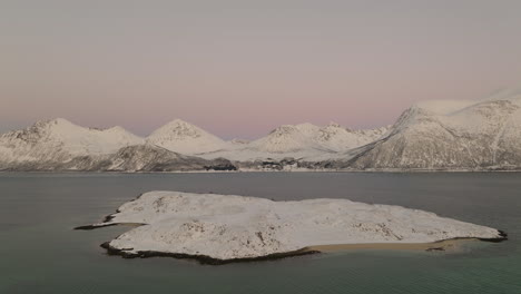 Snow-covered-island-in-middle-of-fjord,-white-winter-landscape