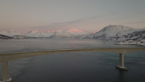 Drohnenschuss,-Der-über-Die-Sommaroy-Brücke-In-Norwegen-Mit-Bergen-Und-Ozean-Fliegt