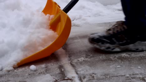 A-plastic-snow-shovel-clearing-snow-from-a-driveway