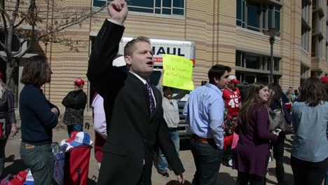 A-Young-White-Male-In-A-Suit-Taunts-Anti-Trump-Protestors-Outside-Of-A-Political-Rally,-Republican-Iowa-Caucus