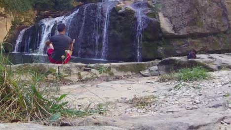 Young-person-relaxing-near-majestic-waterfall,-back-slow-motion-shot