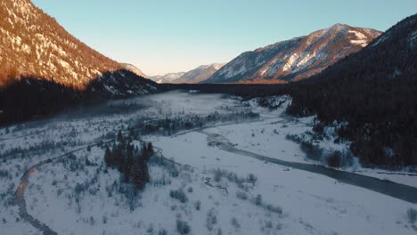 Bavarian-Austrian-alps-scenic-mountain-river-valley-with-fresh-water-at-Sylvensteinspeicher-by-sunset-sunshine,-winter-snow-riverbed,-trees-and-forest-and-mountains