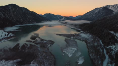 Scenic-Bavarian-Austrian-alps-mountain-river-valley-with-fresh-water-at-Sylvensteinspeicher-by-sunshine-sunset,-winter-snow-riverbed,-trees-and-forest-and-mountains
