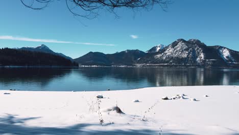 Beach-covered-in-white-snow-at-Lake-Walchensee-in-Bavaria,-south-Germany-in-the-alps-mountains-close-to-Austria