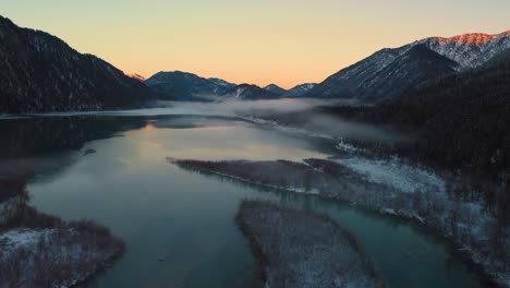 Scenic-mountain-river-valley-with-fresh-water-in-the-Bavarian-Austrian-Alps-at-Sylvensteinspeicher-by-sunshine-sunset,-winter-snow-riverbed-along-trees-and-forest-and-mountains