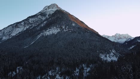 Montaña-Enorme-E-Impresionante-Con-Bosques-Y-árboles-En-Invierno-Con-Nieve-Y-Hielo-En-Las-Idílicas-Y-Escénicas-Montañas-De-Los-Alpes-Austriacos-Bávaros-Con-Picos-Rojos-Al-Atardecer