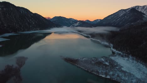 Bavarian-Austrian-alps-mountain-river-valley-with-fresh-water-at-Sylvensteinspeicher-by-sunshine-sunset,-winter-snow-riverbed-along-trees-and-forest-and-mountains
