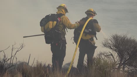 Feuerwehrleute-Setzen-Einen-Schlauch-Und-Wasser-Gegen-Die-Flammen-Des-Alisal-feuers-Ein,-Das-Entlang-Der-Küste-Von-Gaviota-Im-Bezirk-Santa-Barbara-Brennt