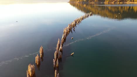 Evening-Sunset-Drone-Aerial-Over-Glenbrook,-Lake-Tahoe,-Nevada,-With-Old-Pier-Pilings-Coming-Out-Of-Calm-Water