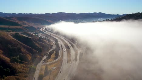 Antena-Sobre-Niebla-Y-Nubes-A-Lo-Largo-De-Una-Carretera-A-Través-De-Las-Estribaciones-De-California-Cerca-De-Ojai-California