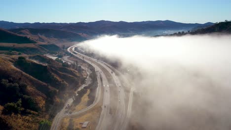 Aerial-Over-Fog-And-Clouds-Along-A-Highway-Through-The-California-Foothills-Near-Ojai-California