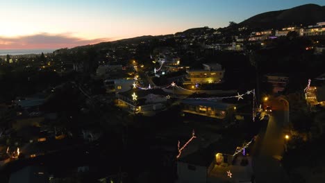 Aerial-Over-The-Hillsides-Of-Southern-California-Ventura-Los-Angeles-At-Night-At-Sunset-With-Homes-Decorated-With-Christmas-Lights-And-Stars