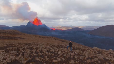 Gute-Luftaufnahme-Eines-Mannes,-Der-Steht-Und-Den-Ausbruch-Des-Fagradalsfjall-Vulkans-In-Island-Beobachtet