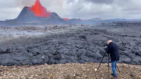 A-Man-Films-A-Volcanic-Eruption-From-Up-Close-With-A-Camera-And-Tripod-In-Fagradalsfjall-Eruption-Iceland