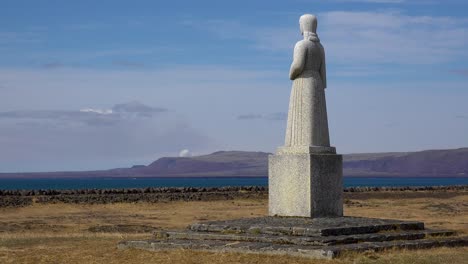 Eine-Statue-überblickt-Eine-Entfernte-Rauchwolke-Eines-Ausbrechenden-Vulkans,-Island