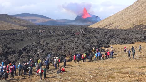 Tourists-Watch-The-Eruption-Of-The-Fagradalsfjall-Volcano-From-The-Leading-Edge-Of-The-Lava-Flow-In-Iceland