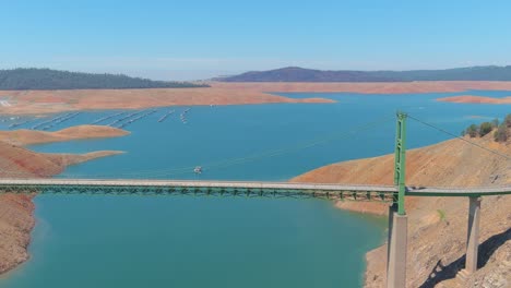 Inquietante-Antena-Sobre-El-Lago-Oroville-De-California-Azotado-Por-La-Sequía-Con-Bajos-Niveles-De-Agua,-Costa-En-Retroceso-Y-Gran-Cruce-De-Puentes