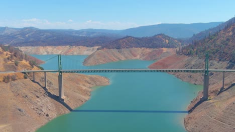 Disturbing-Aerial-Over-Drought-Stricken-California-Lake-Oroville-With-Low-Water-Levels,-Receding-Shoreline-And-Large-Bridge-Crossing