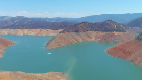 Disturbing-Aerial-Over-Drought-Stricken-California-Lake-Oroville-With-Low-Water-Levels,-Receding-Shoreline-And-Boats-In-The-Low-Water