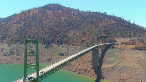 Beunruhigende-Luft-über-Dem-Von-Der-Dürre-Betroffenen-Kalifornischen-Oroville-see-Mit-Niedrigem-Wasserstand,-Zurückweichender-Küstenlinie-Und-Großer-Brückenüberquerung