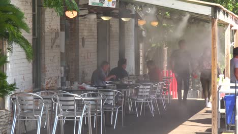 Diners-Keep-Cool-Under-Water-Blowing-Fans-At-An-Austin-Texas-Restaurant-In-The-Heat-Of-Summer