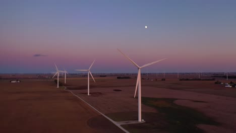 Excellent-Dusk-Aerial-Of-Windmills-Generating-Clean-Electricity-On-The-Flat-Farmlands-Of-Indiana,-Illinois,-With-Moon-Rising