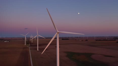 Excellent-Dusk-Aerial-Of-Windmills-Generating-Clean-Electricity-On-The-Flat-Farmlands-Of-Indiana,-Illinois,-With-Moon-Rising